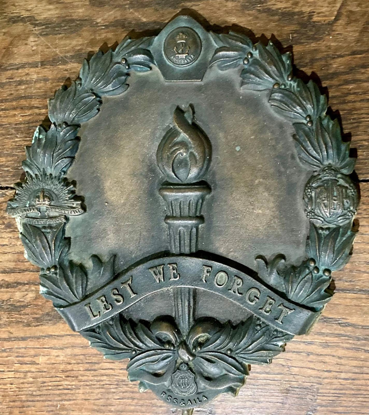 Returned Sailor's Soldier's Airmen's Imperial League (RSSAILA) bronze plaque featuring a laurel wreath with the three service badges, the Legacy torch and the words 'Lest we forget'