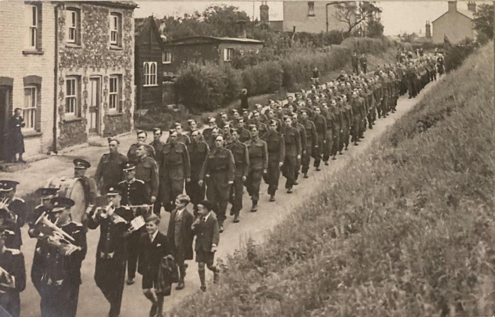 Photograph showing large procession of airmen going through an English village