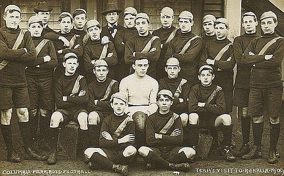 Black and white photo of young men in a uniform posing for a photograph