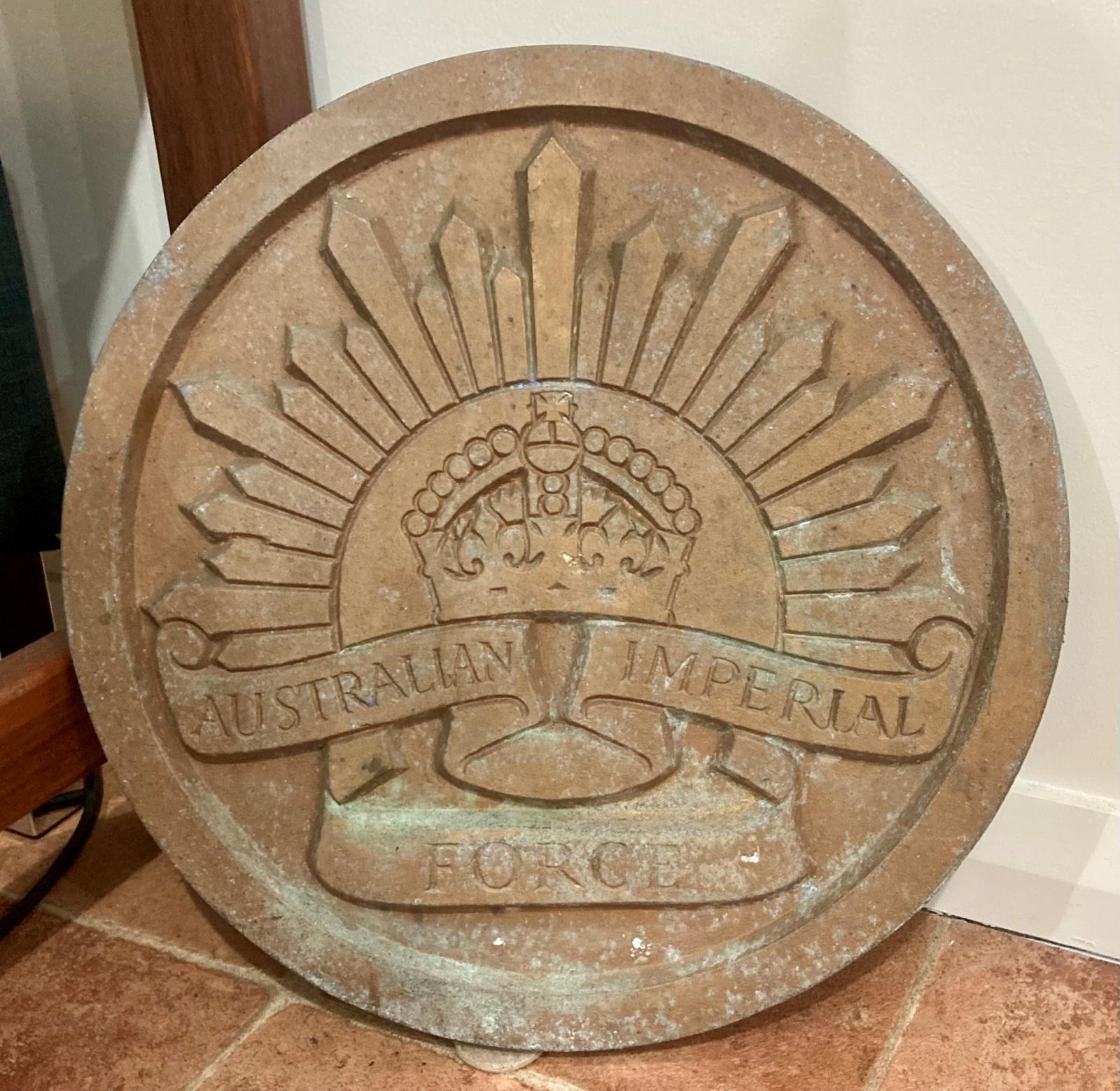 Circular cast metal plaque with a Rising Sun badge