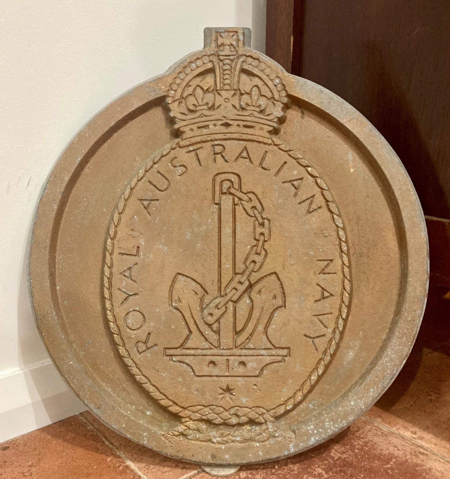 Circular cast metal plaque with an anchor and chain beneath a crown