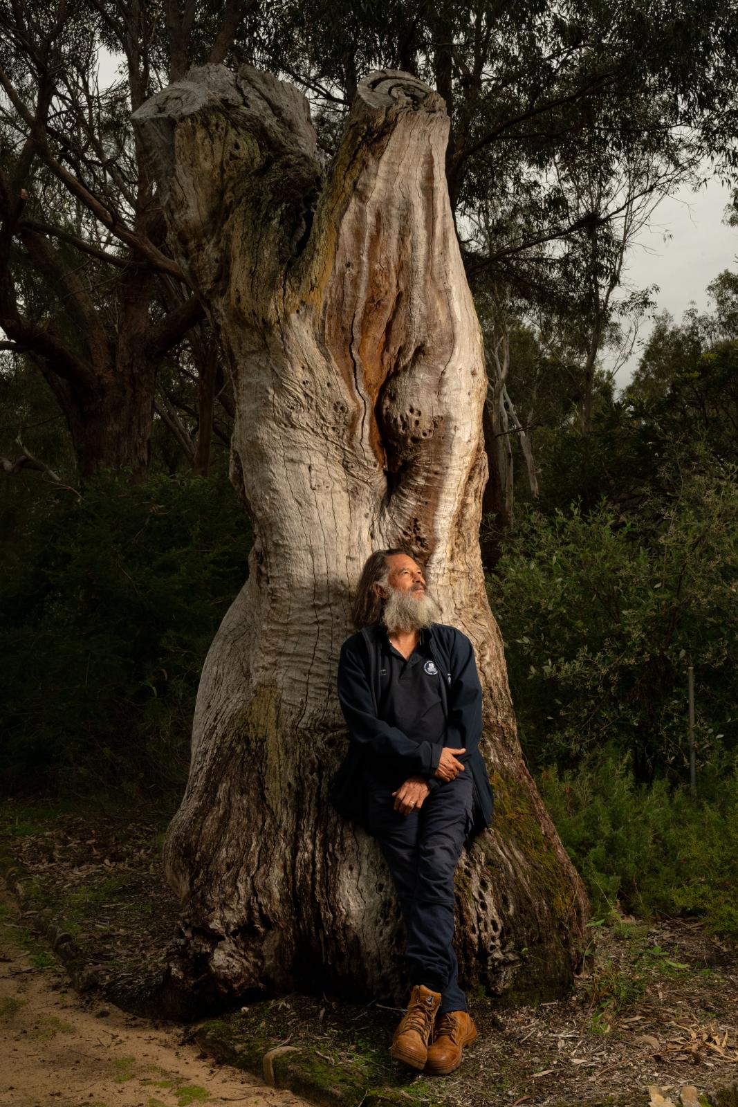 Derek Nannup leaning against a tree stump