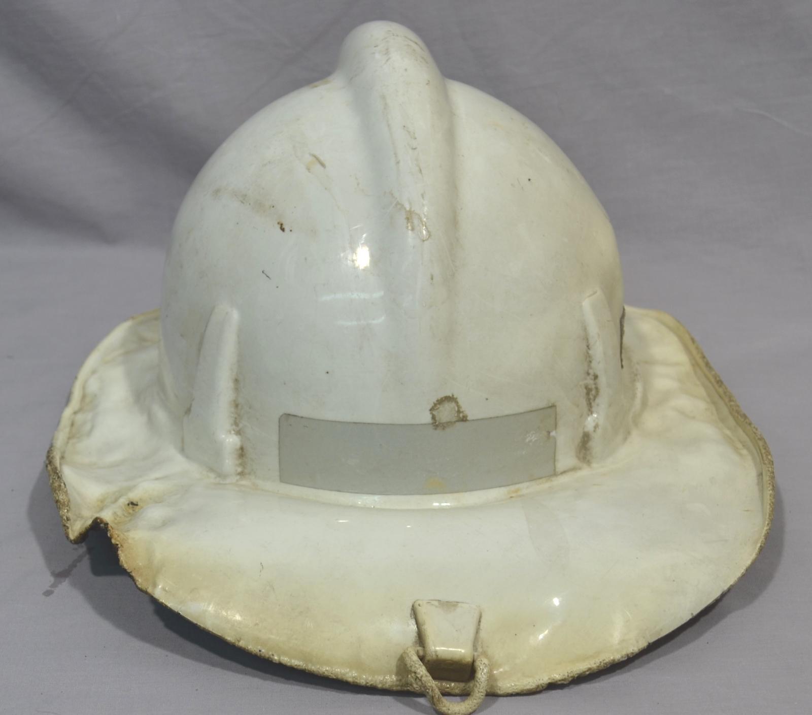 View of the back of a firefighter's fibreglass helmet. The helmet has been fire damaged and melted in places on the sides and back.