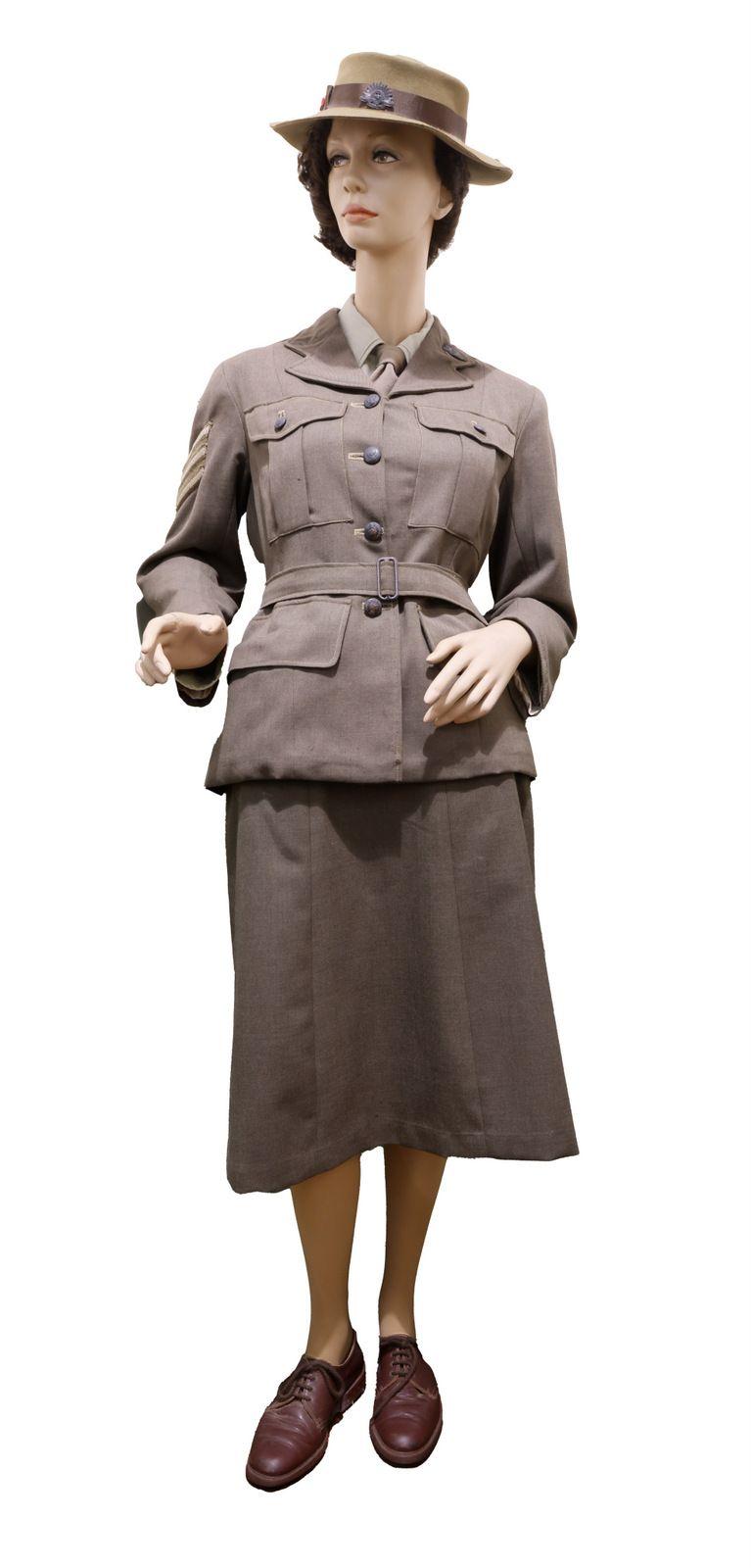 "Mannequin dressed in a World War 2 era, Australian Womens Army Service winter uniform consisting of a tailored jacket with multiple pockets, a matching knee-length skirt, a hat with a wide brim, and leather shoes.