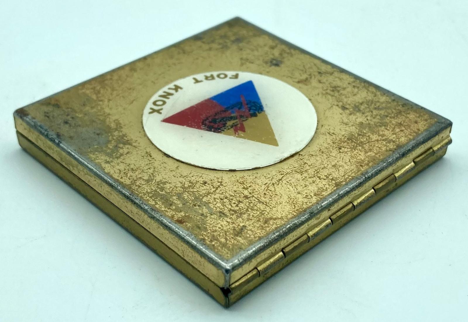 Gold-toned powder compact with Fort Knox logo - oblique back view showing hinge