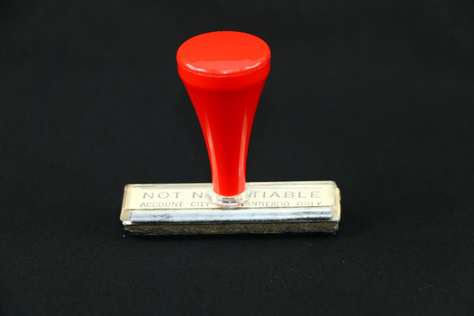 A rectangular rubber, City of Wanneroo Not Negotiable stamp, which has a red plastic handle.