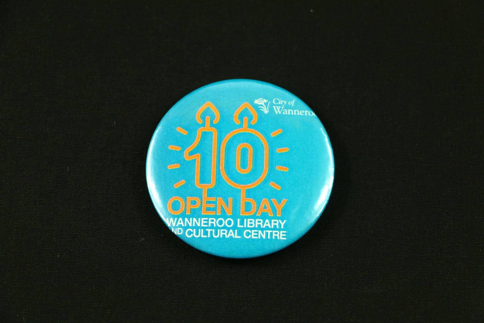 Circular badge with slightly domed plastic face and silver metal backing, commemorating the 10th Anniversary of the Wanneroo Library & Cultural Centre.