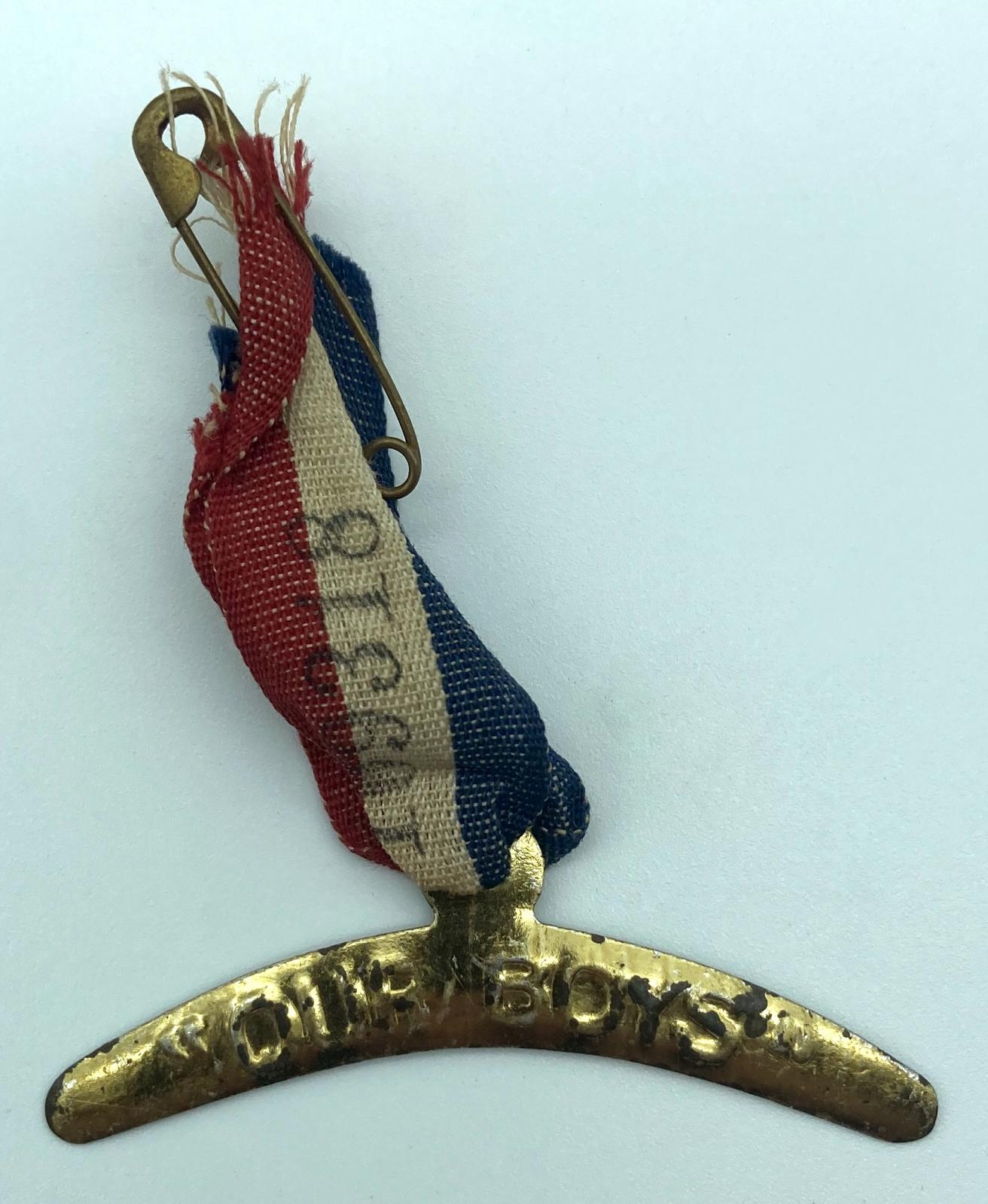 WWI fundraising metal boomerang on a tricolour ribbon supporting 'Our Boys'