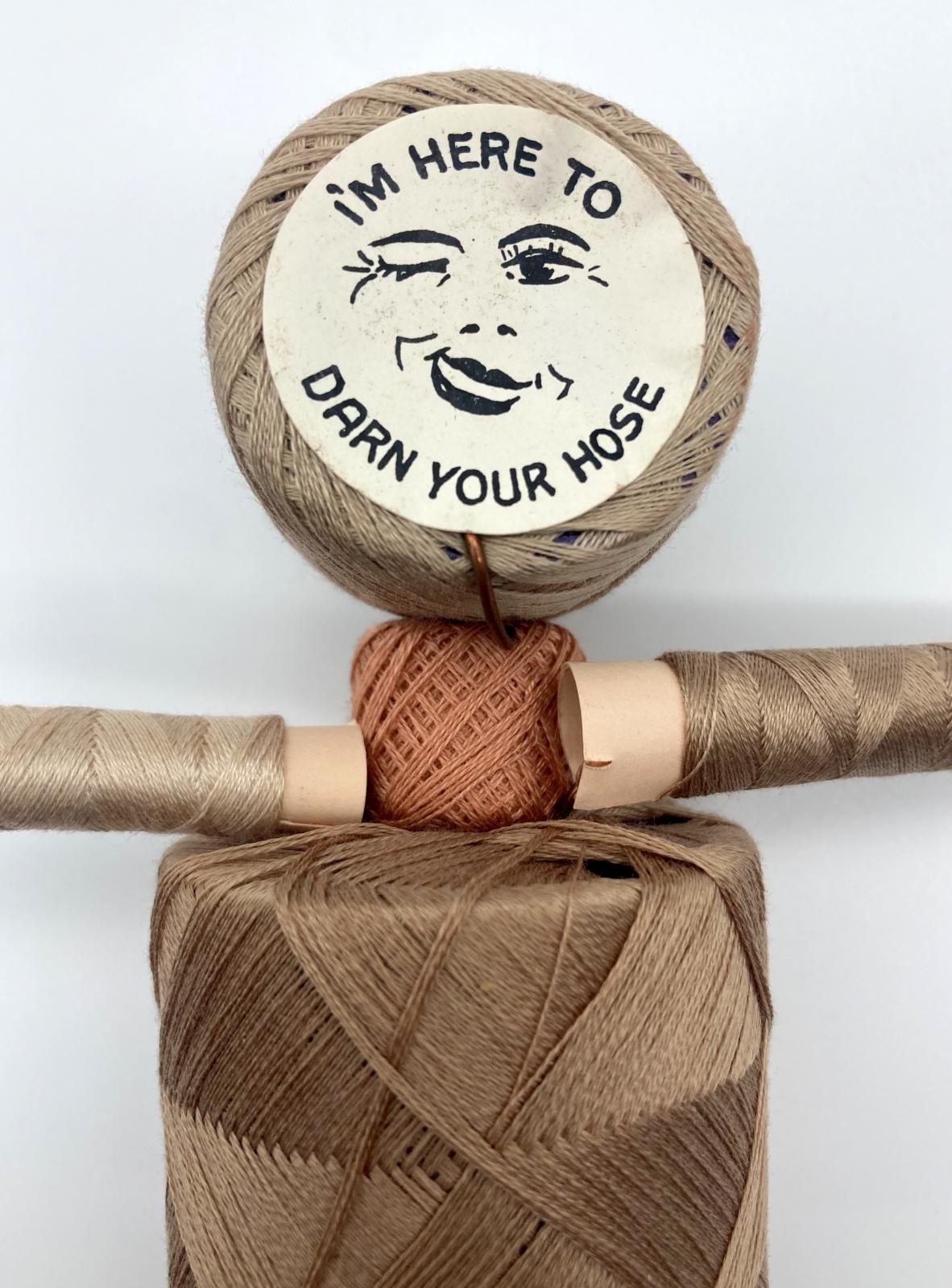 Close up of face of WWII 'Make Do and Mend' pantyhose repair kit in form of doll