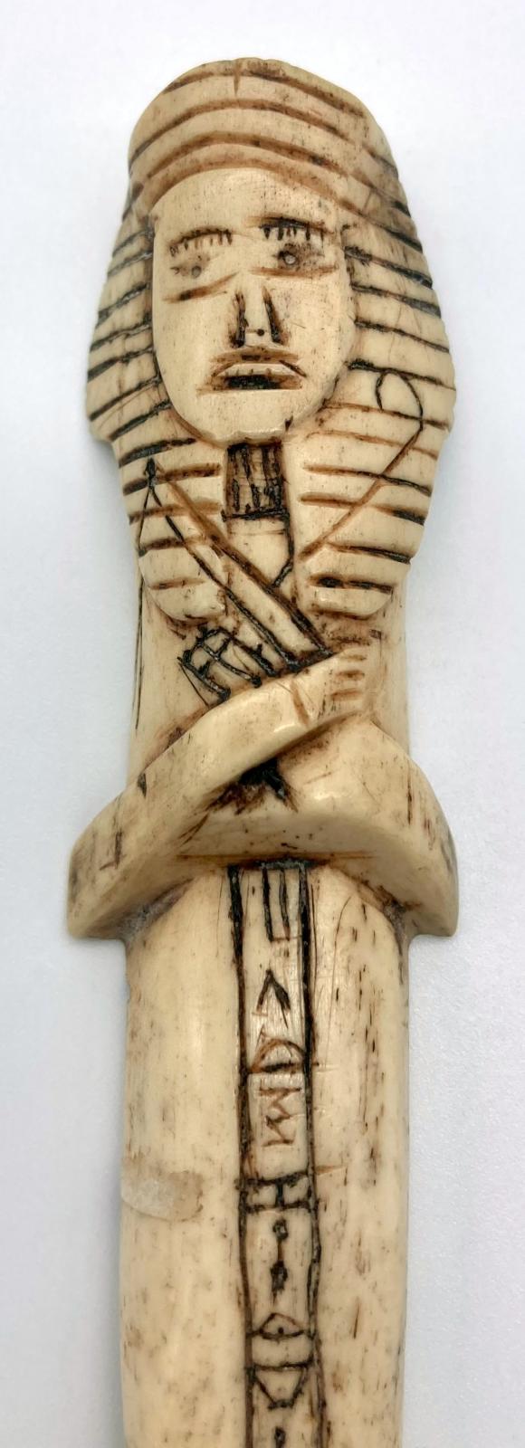 Close up of Carved camel bone in the form of an Egyptian shabti