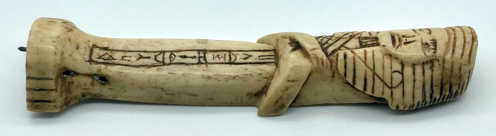 Other side view of carved camel bone in the form of an Egyptian shabti