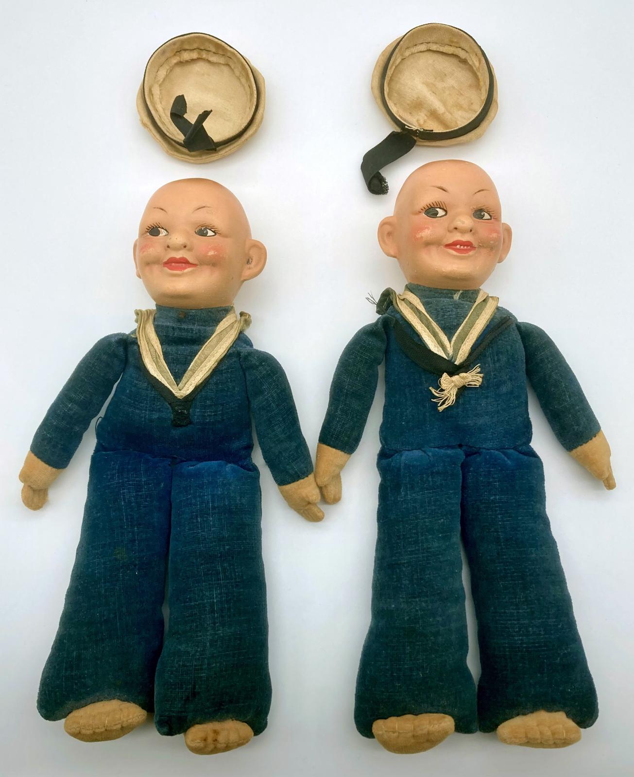 Front views of souvenir sailor dolls showing caps removed and bald heads