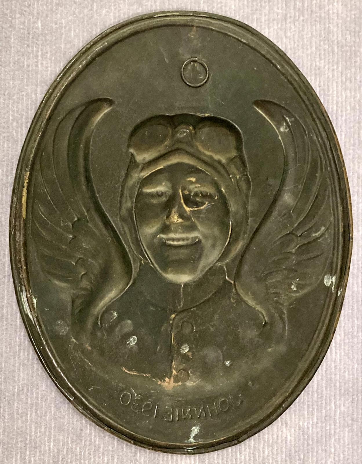 Reverse of pressed brass wall plaque featuring the relief portrait of aviatrix Amy Johnson