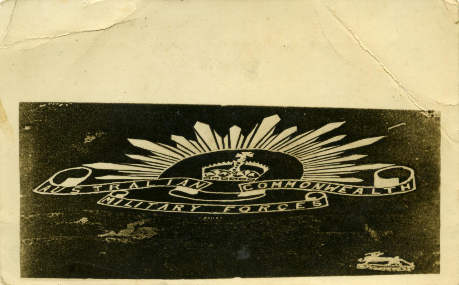 RPPC of Australian Rising Sun badge carved into chalk hills in Wiltshire