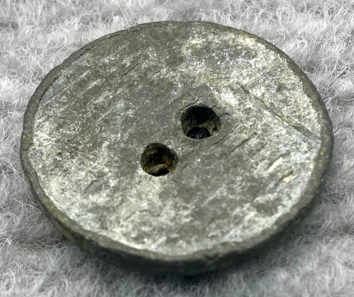 Oblique view of lead button from clothing worn by munitions worker