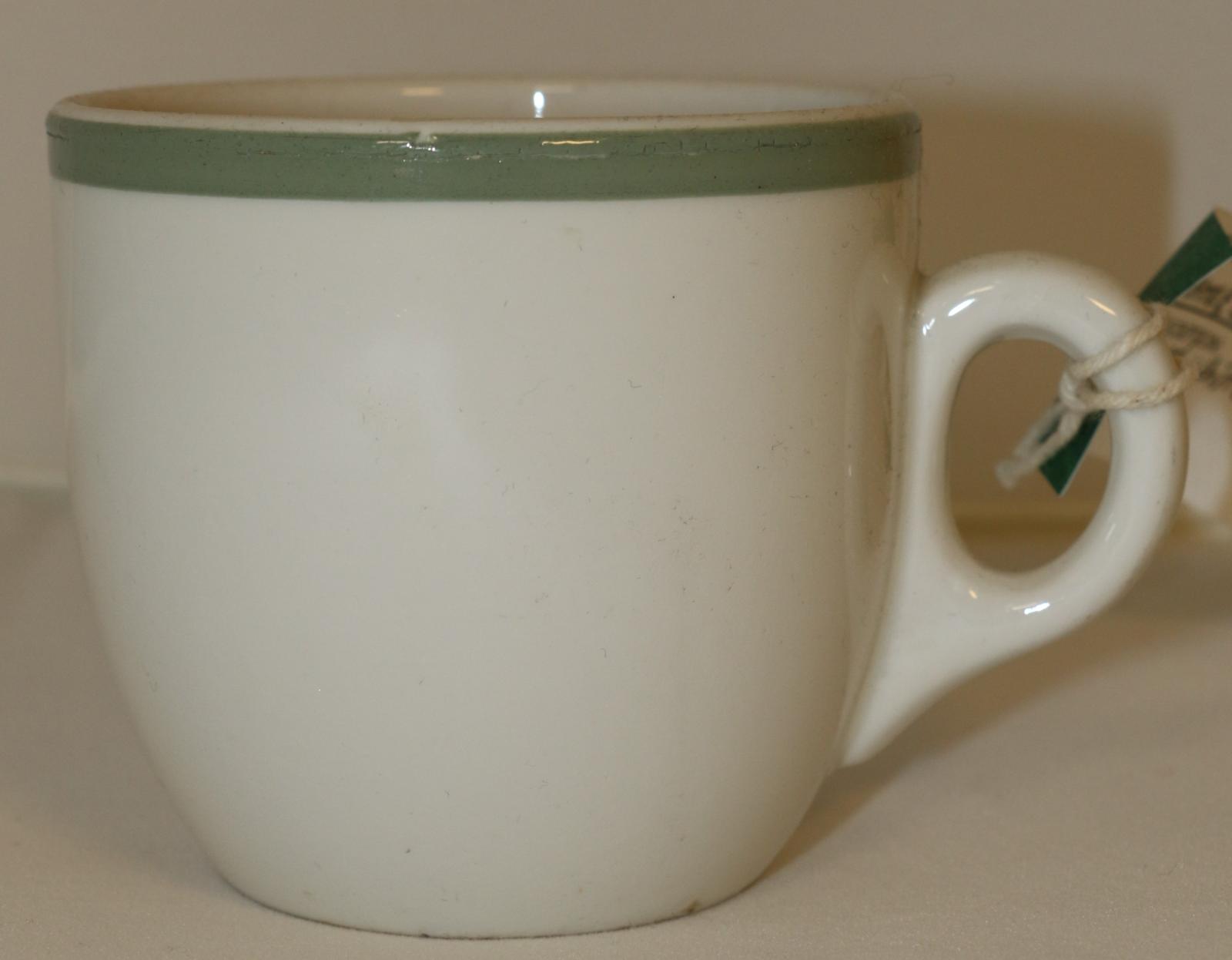 Off white tea cup of simple shape, green band around lip of cup.