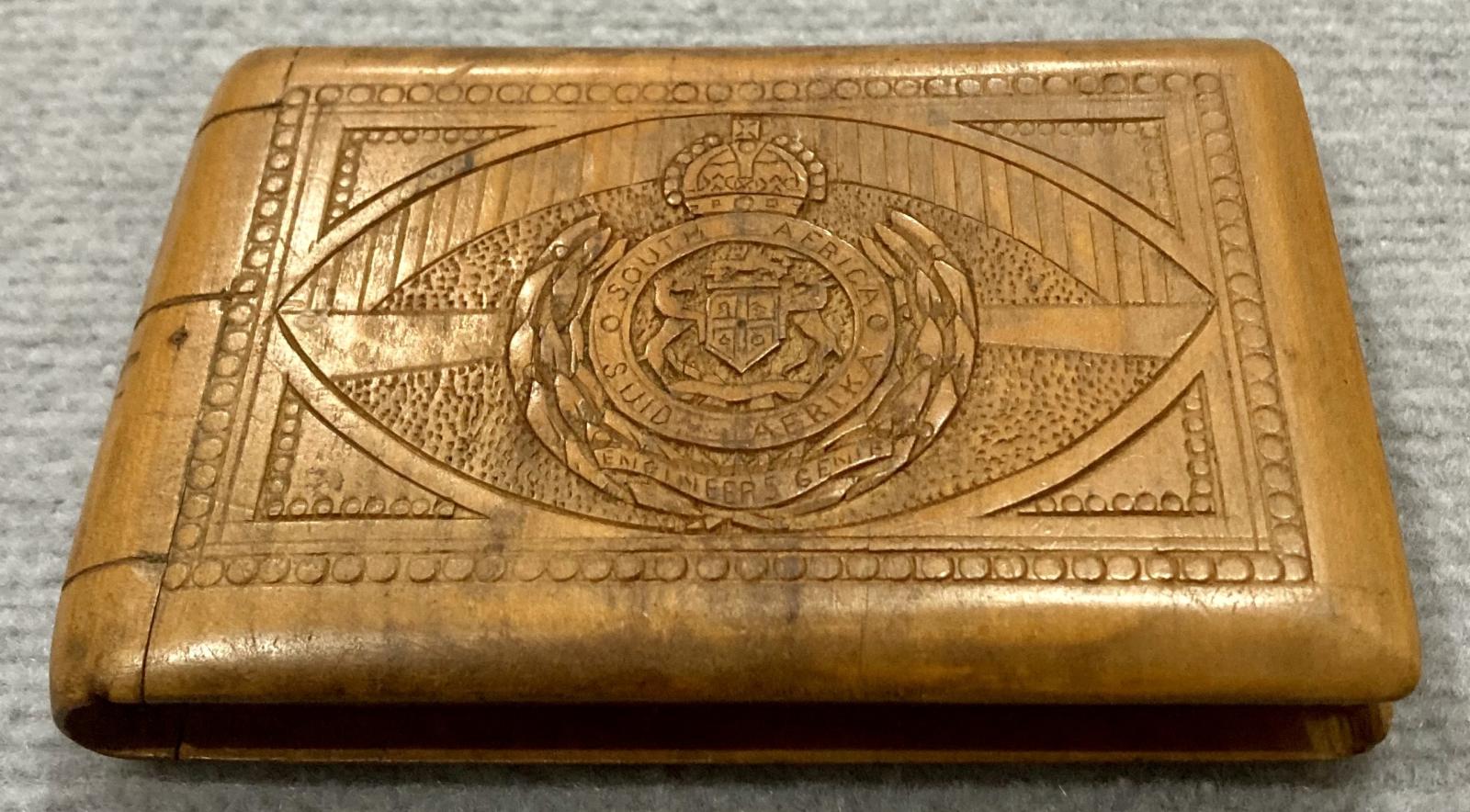 Side view of front of souvenir timber case featuring carved South African Engineers badge