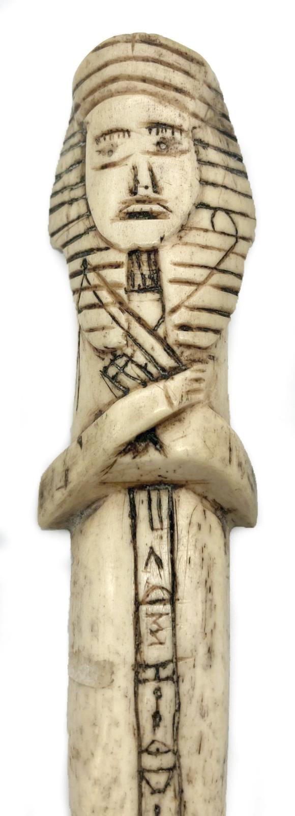 Close up of carved camel bone in the form of an Egyptian shabti