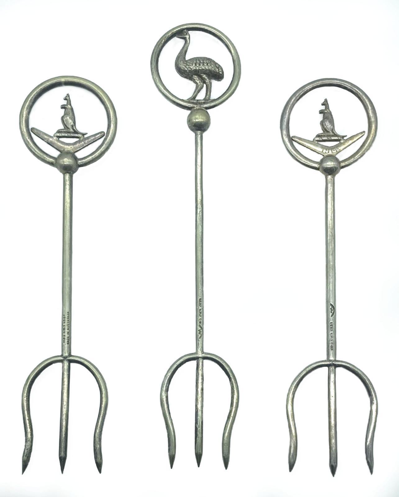 Group of three silver plated trident bread forks with decorative tops