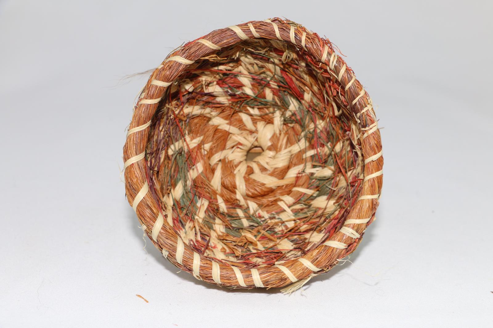 Woven basket with brown, cream, green and red colours mixed together.