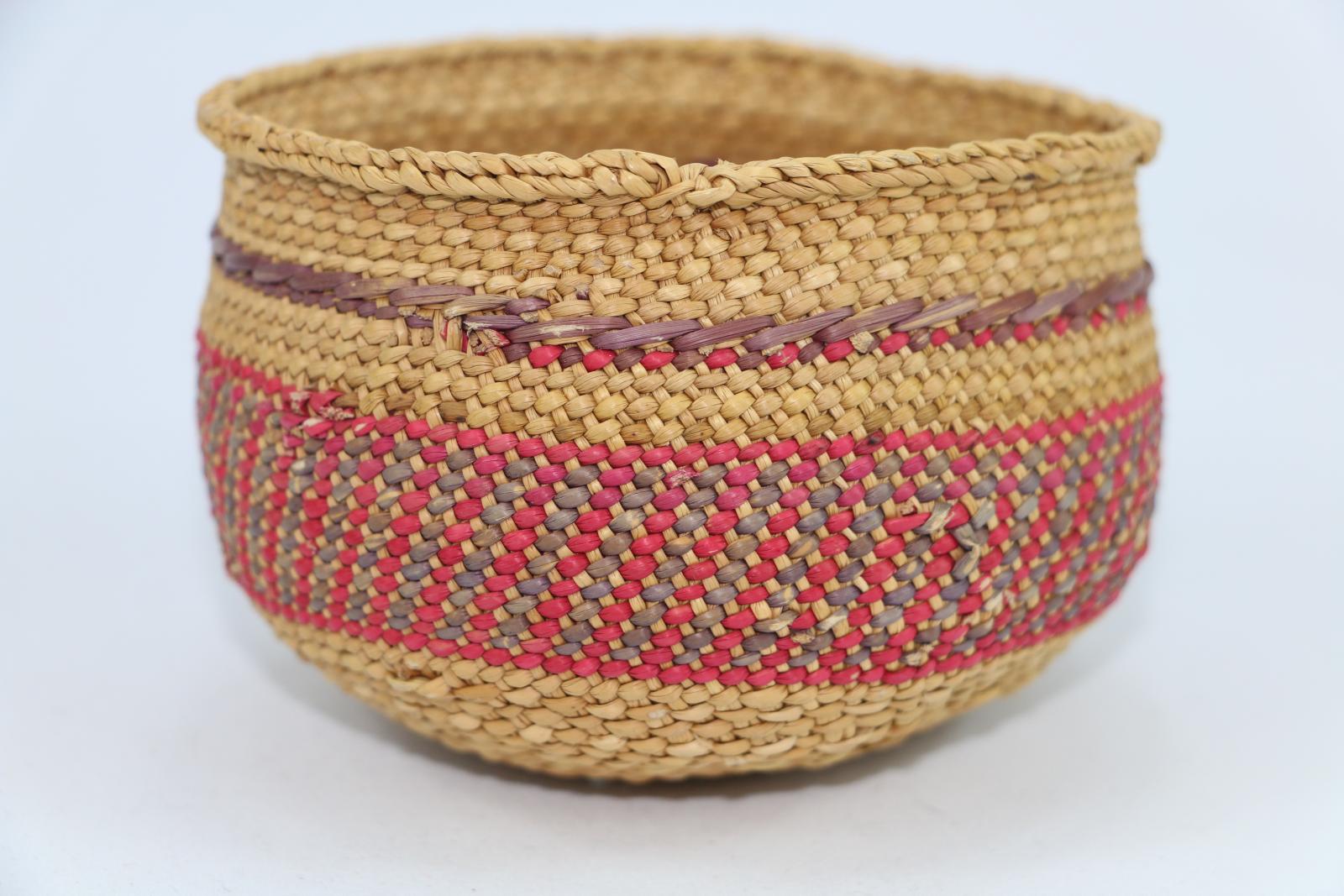 Woven basket made of plant material, with cane, purple and red colours.