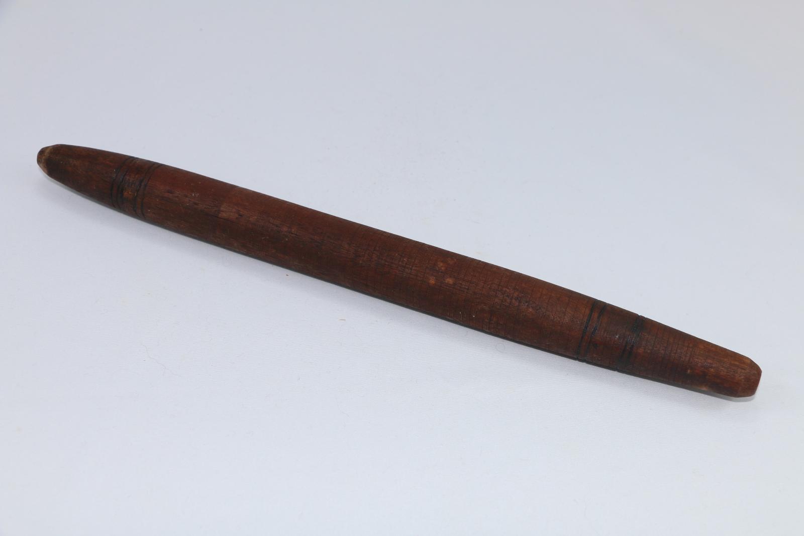 Clapping stick made of dark brown wood with burned and carved decorative elements.