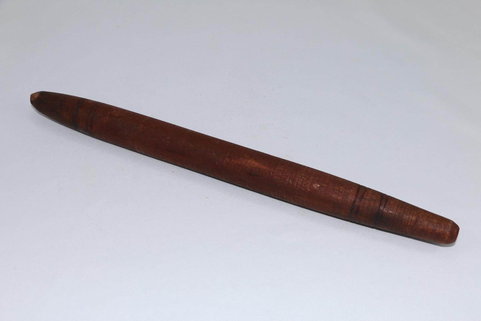 Clapping stick made of dark brown wood with burned and carved decorative elements.