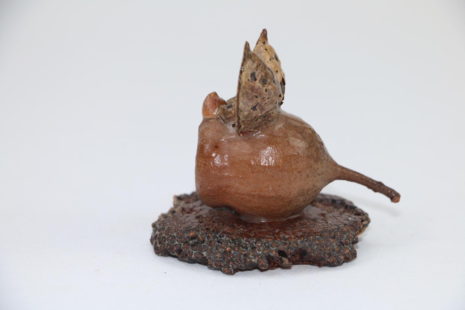 Small mouse figure made from a gumnut and other plants, the figure is on a small circular wooden base.