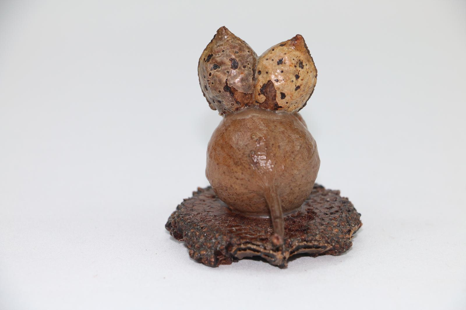 Small mouse figure made from a gumnut and other plants, the figure is on a small circular wooden base.