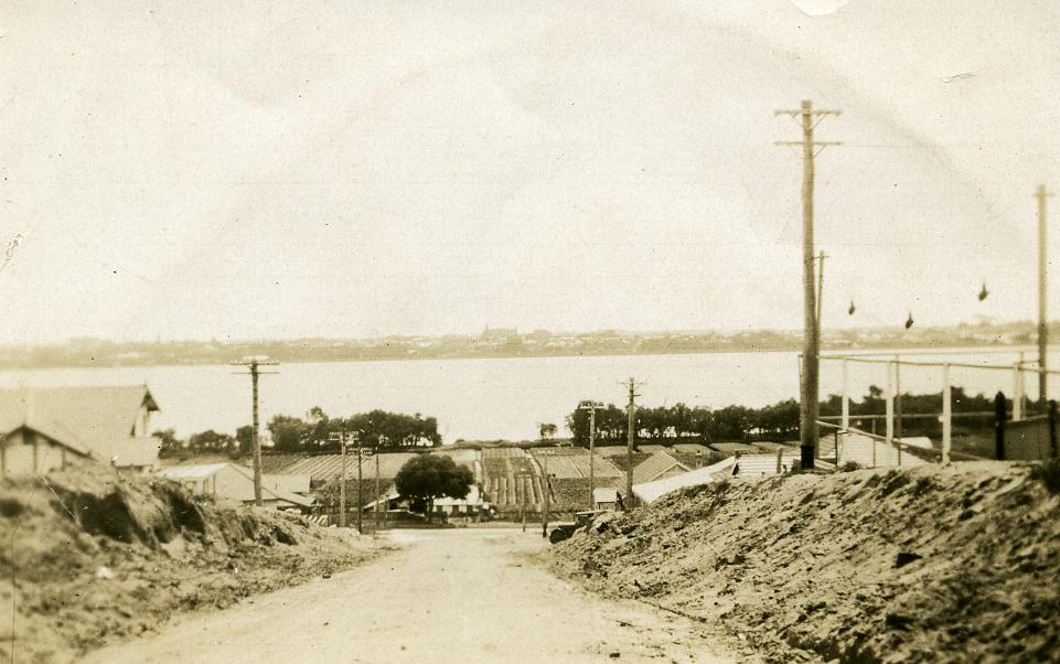 A road leading down to gardens near a river.