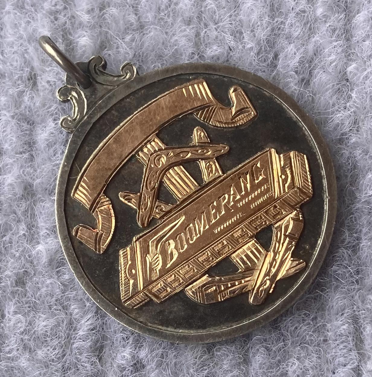Oblique view of prize medallion for Boomerang mouth organ contest 