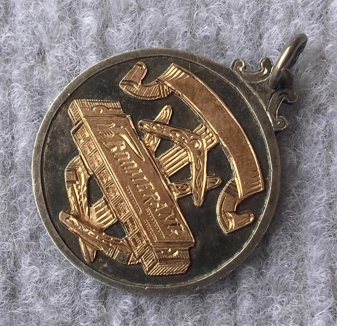 Other oblique view of prize medallion for Boomerang mouth organ contest 