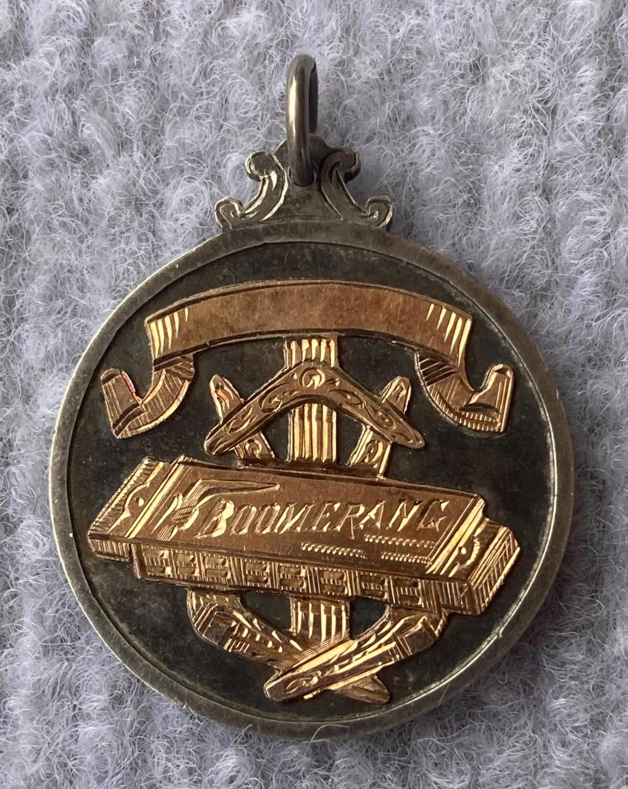 Front view of prize medallion for Boomerang mouth organ contest 