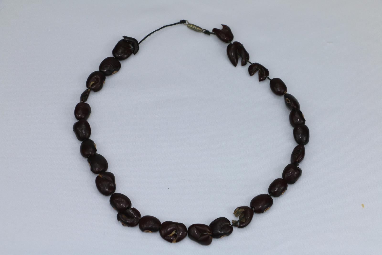 Necklace made from brown seeds, brown thread and metal clasp.