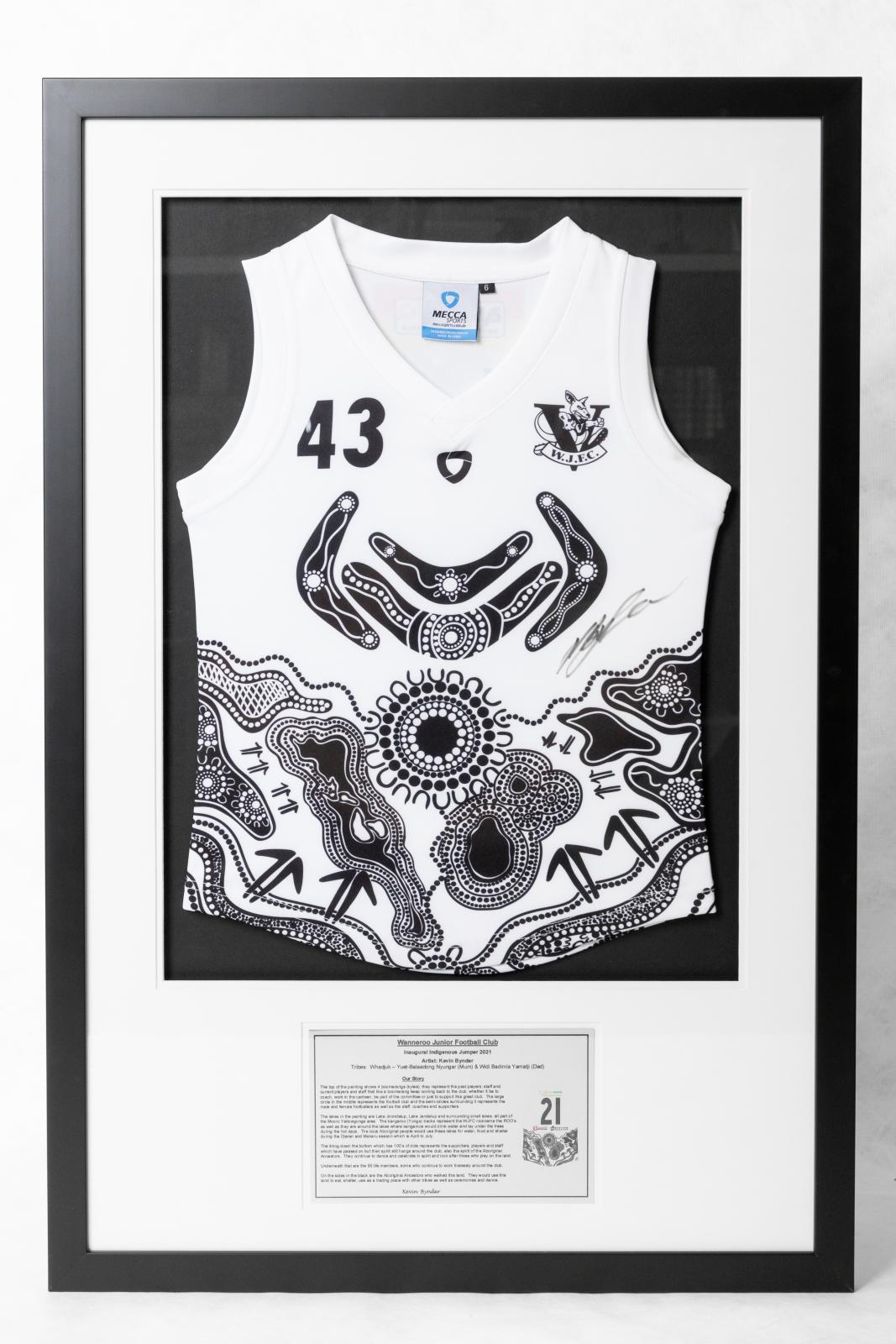 Framed black and white football shirt with First Nations artwork and the number 43 on the top left and the W.J.F.C logo on the top right. The shirt is on black backing with a white border in a black frame. Underneath the shirt is printed label which explains the artwork by Kevin Bynder.