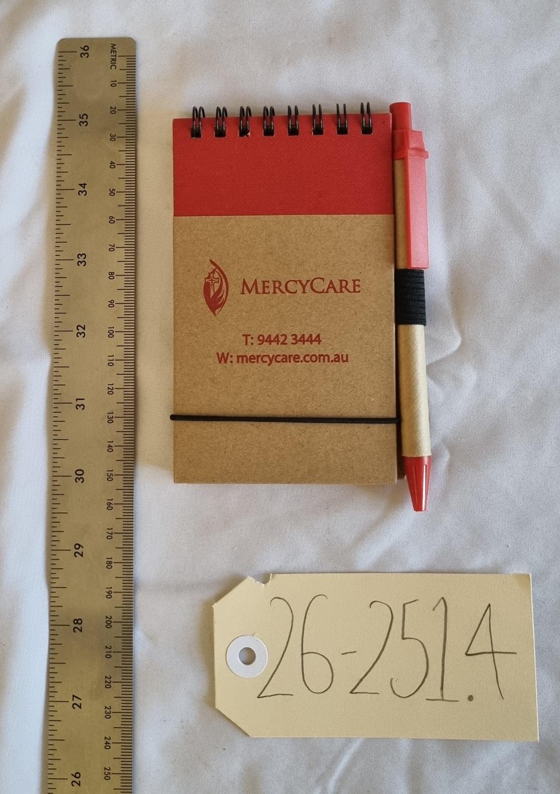 26-251.4 Notepad and Pen with MercyCare Old Logo photo with scale and tag.