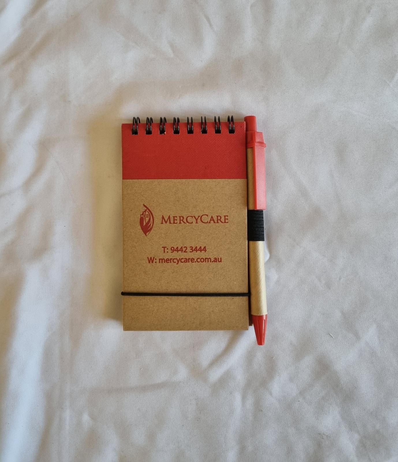 26-251.4 Notepad and Pen with MercyCare Old Logo photo with background front-view.