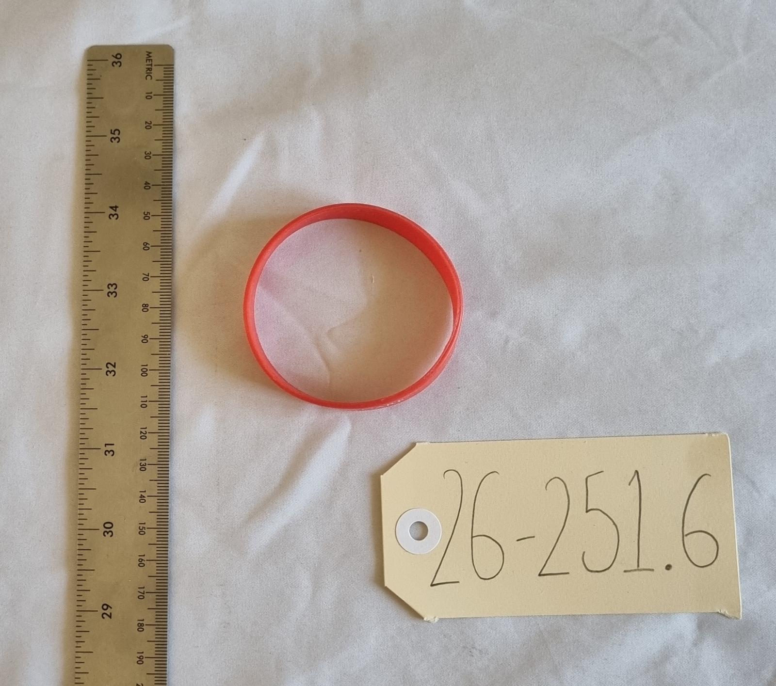 26-251.6 Red Wristband with old MercyCare logo photo with scale and tag.
