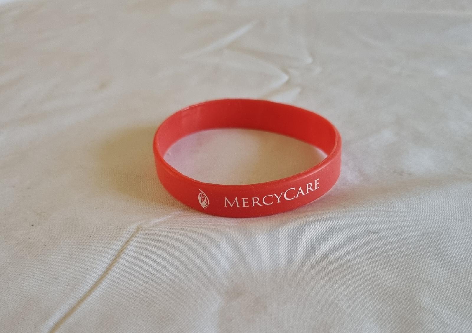 26-251.6 Red Wristband with old MercyCare logo photo with background front-view.