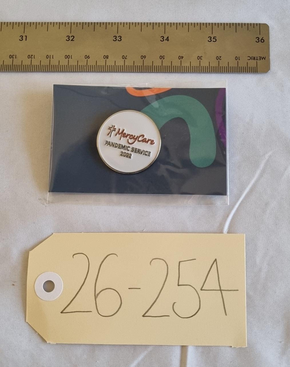 26-254 MercyCare Pandemic Service Badge photo with scale and tag.