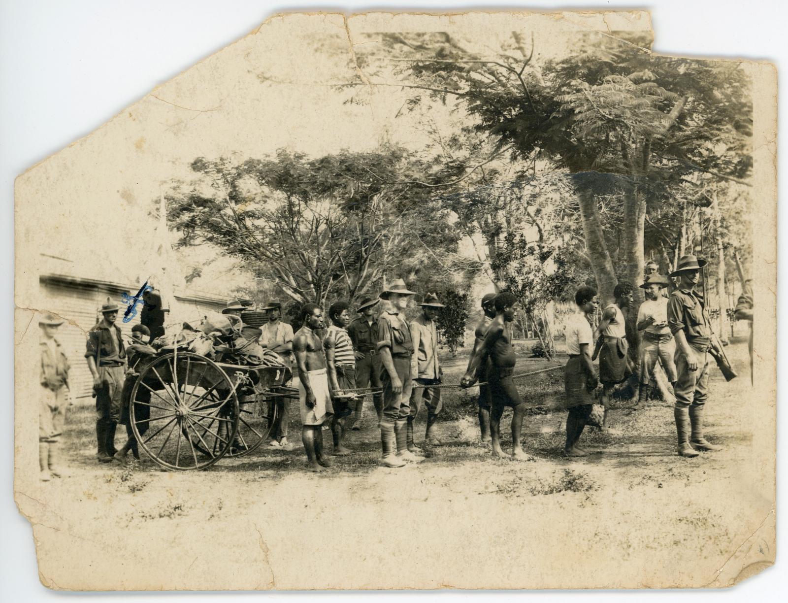 Australian soldiers and New Guinea natives with a wagon of supplies.