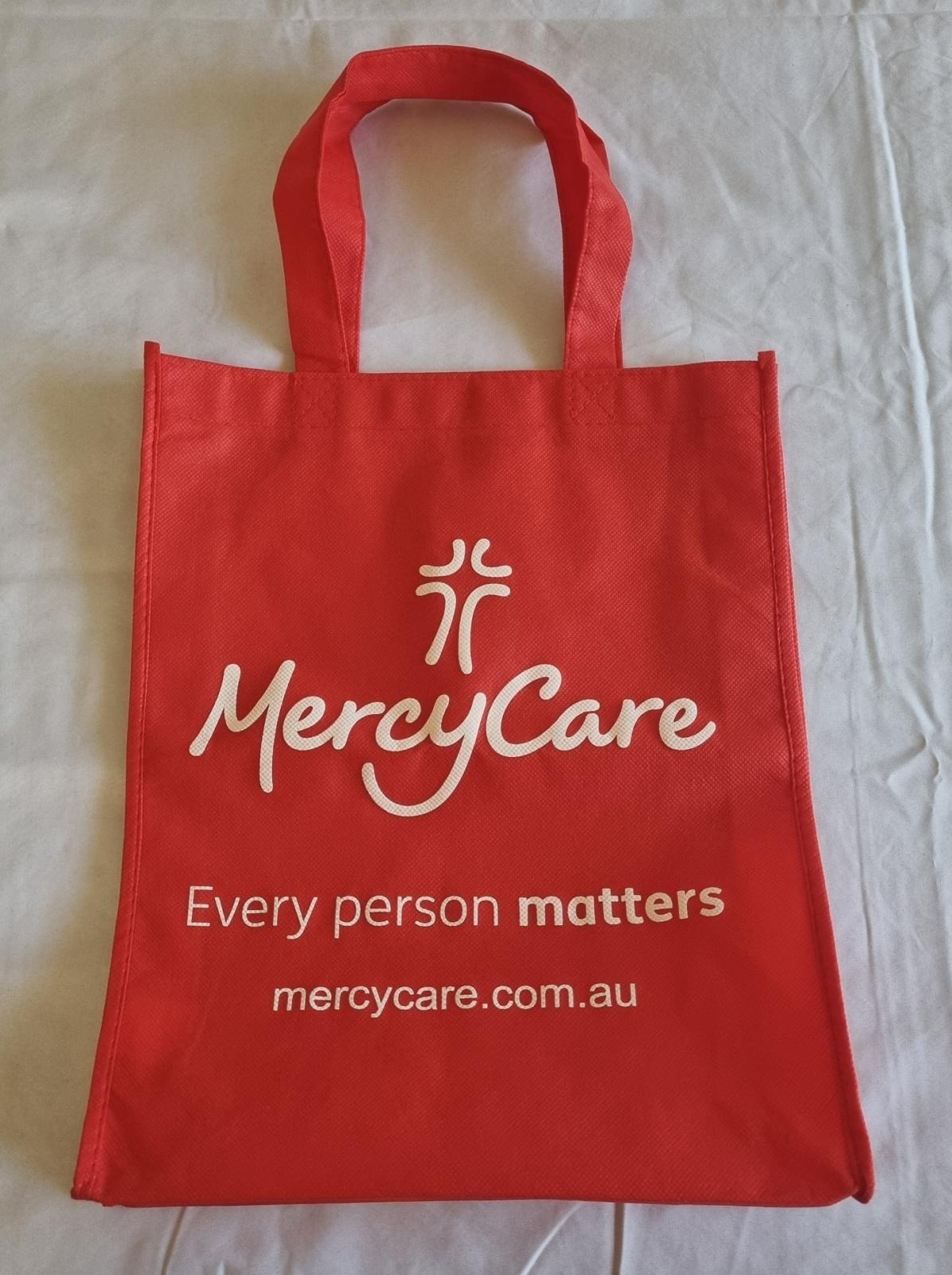 26-259 Red MercyCare bag with the new MercyCare logo photo with background. 