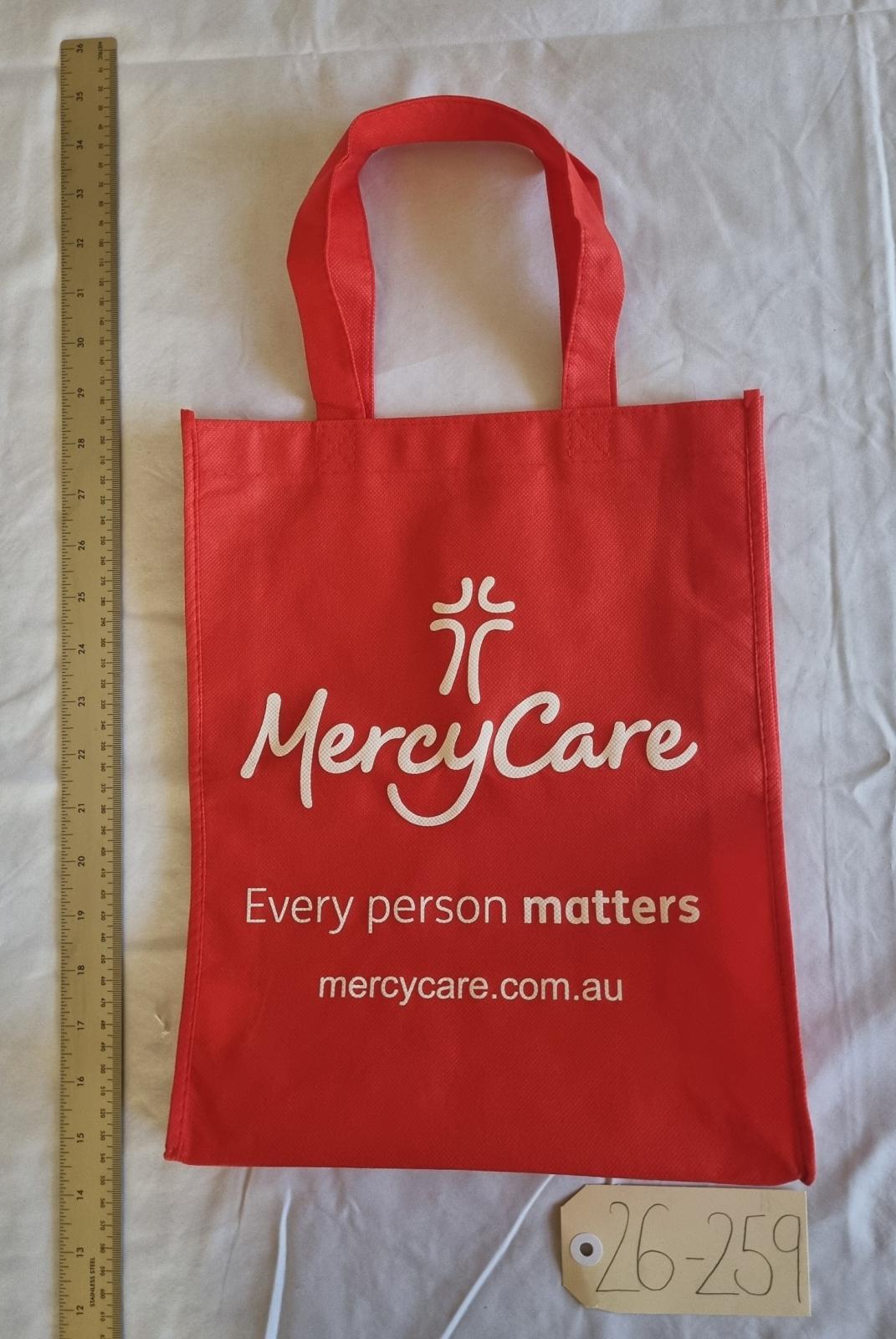 26-259 Red MercyCare bag with the new MercyCare logo photo with scale and tag.