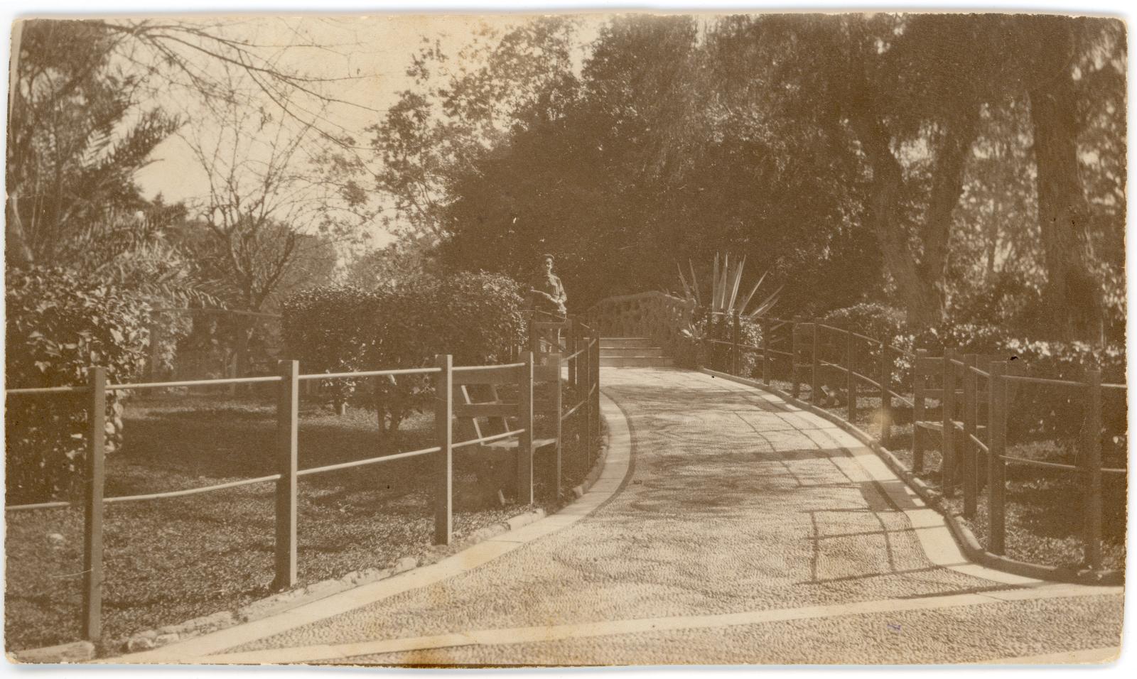 Photograph of a soldier standing on pathway leading through gardens at Giza Zoo, Cairo.