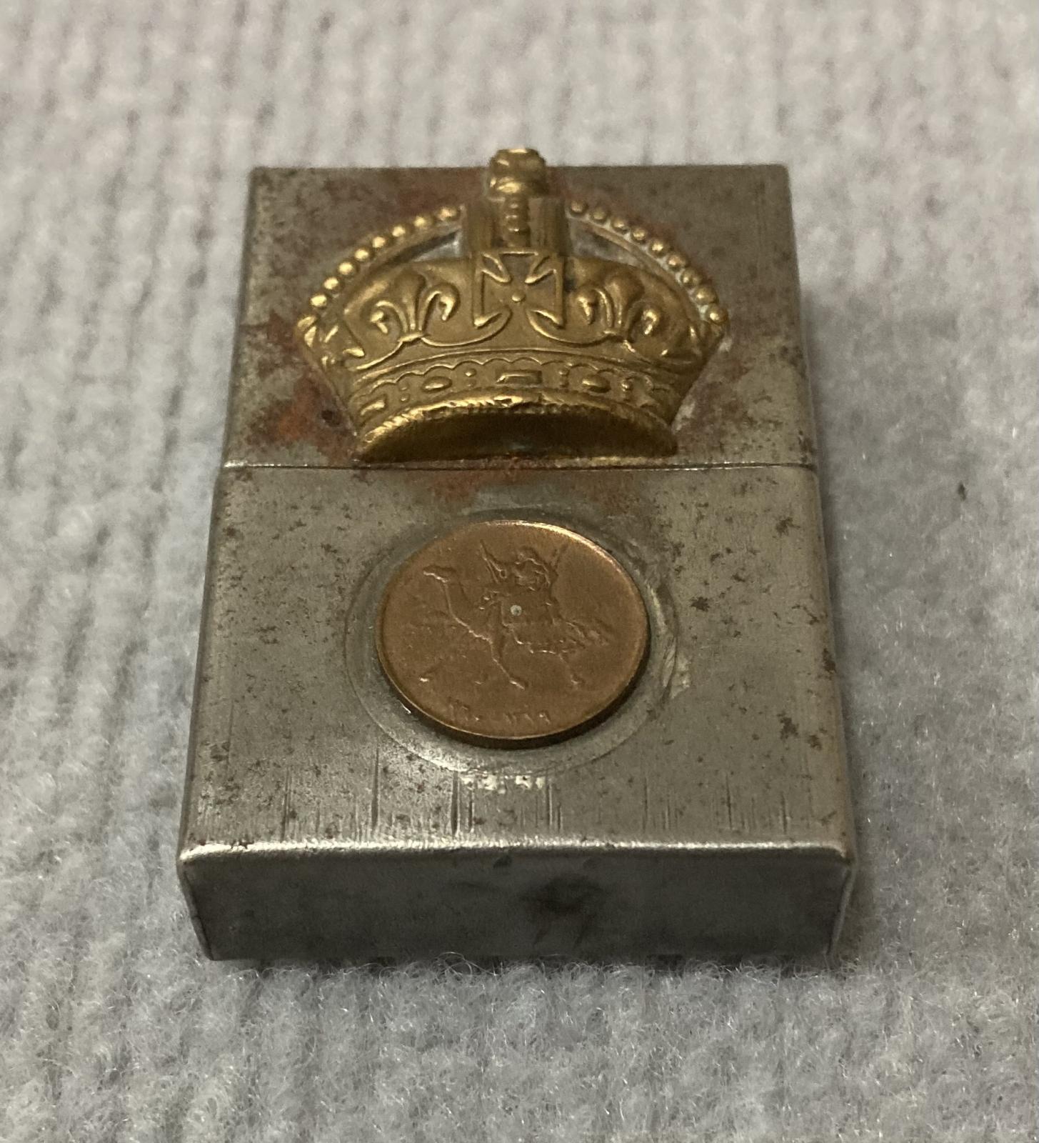 Angled view of metal lighter with attached rank badge and coin