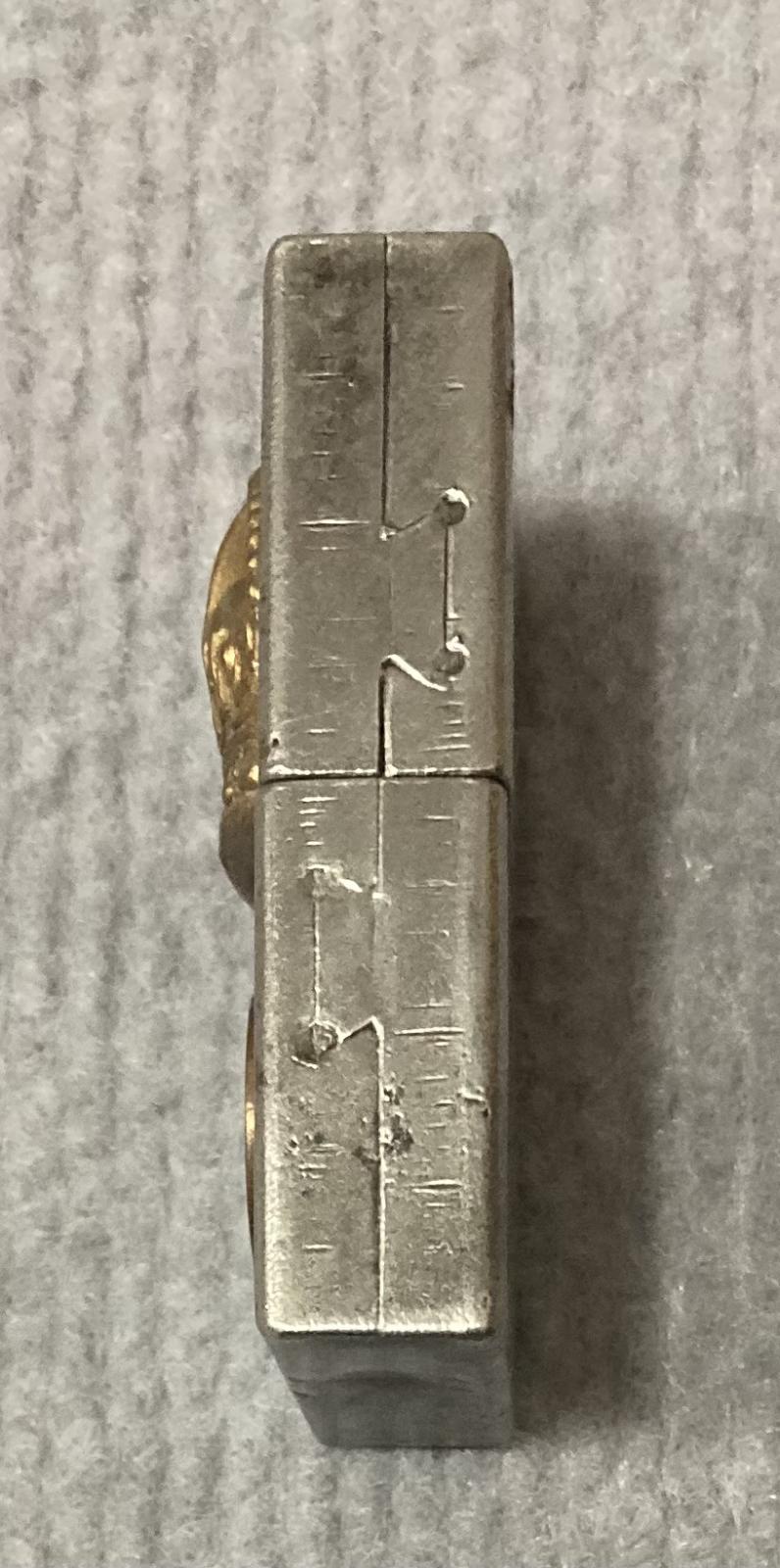 Right side view of metal lighter with attached rank badge and coin