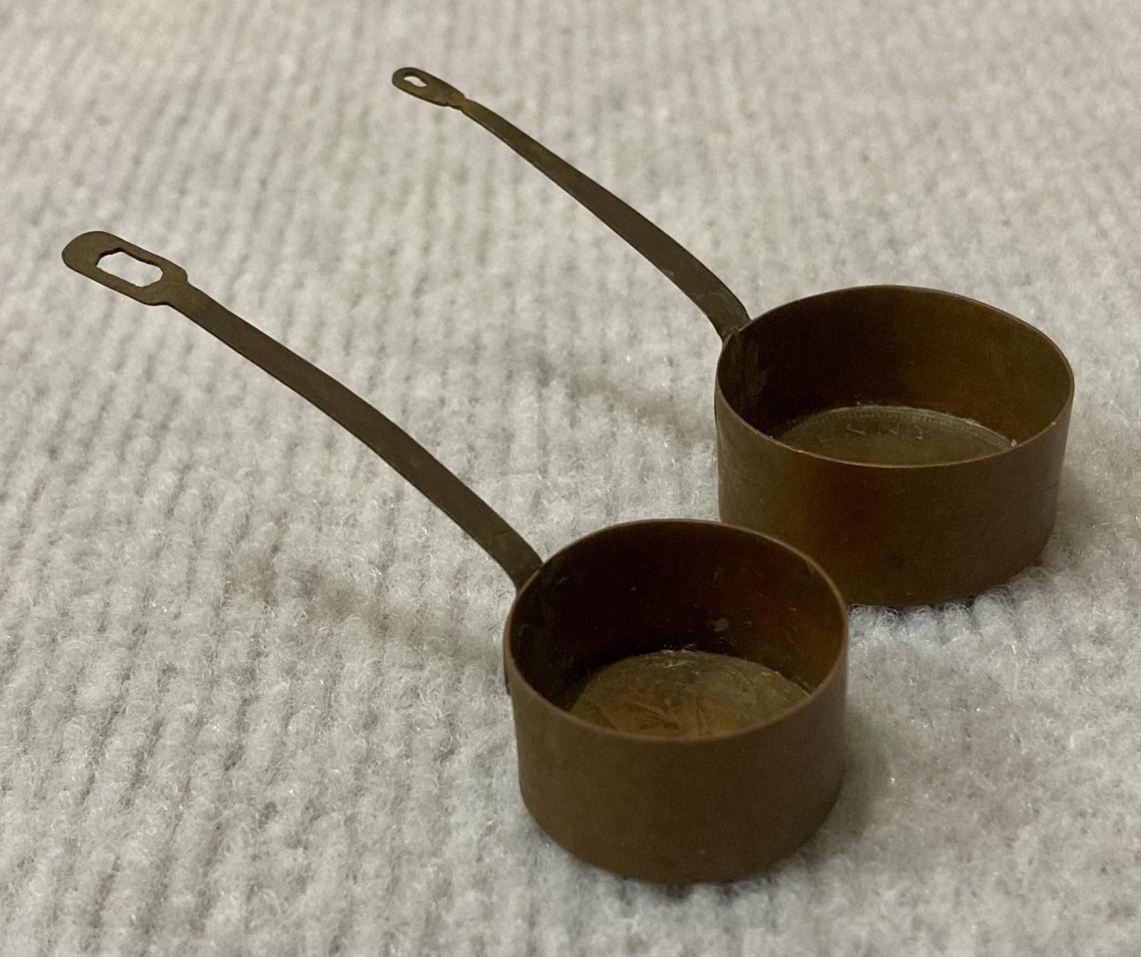 Side view of miniature saucepans made from Australian coins