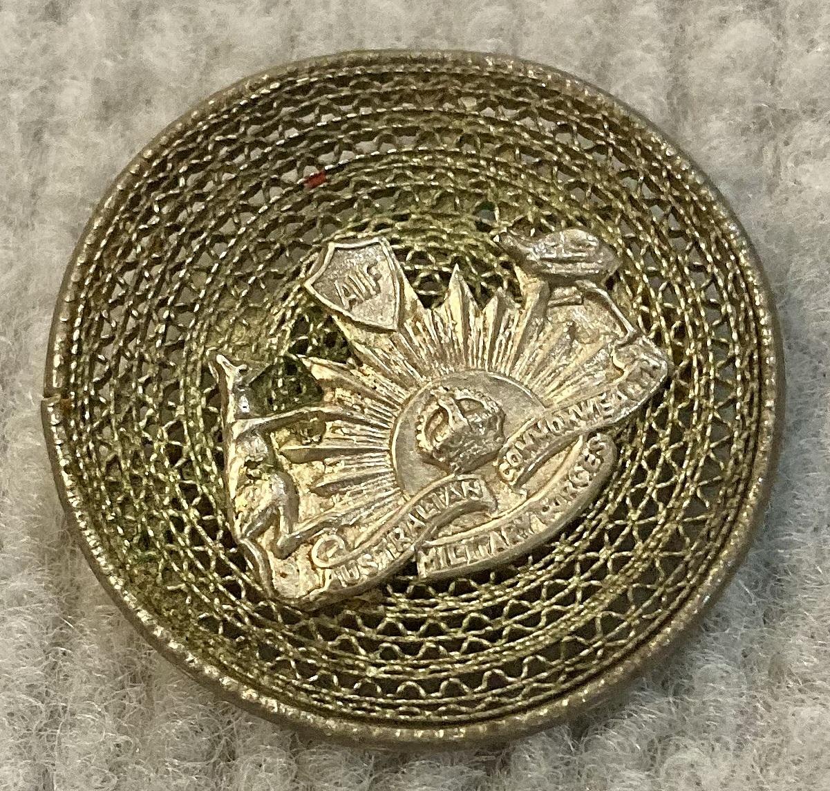 Angled view of WWI A.I.F. sterling silver filigree sweetheart Rising Sun badge