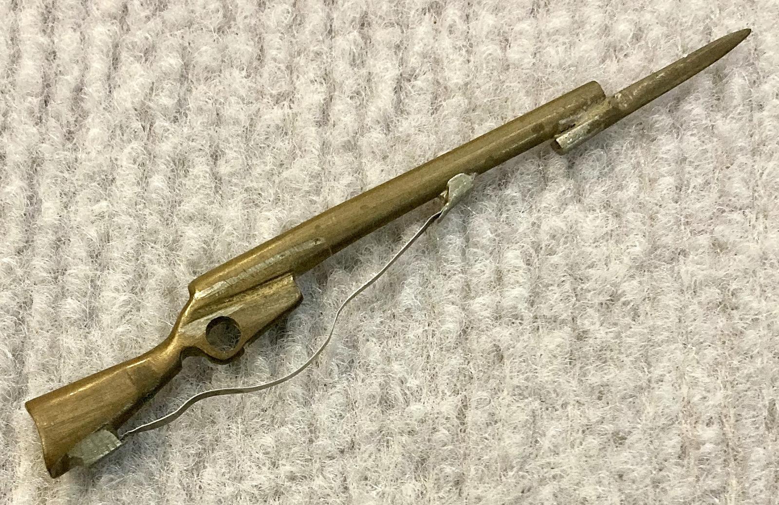 Angled view of miniature brass rifle with bayonet and sling