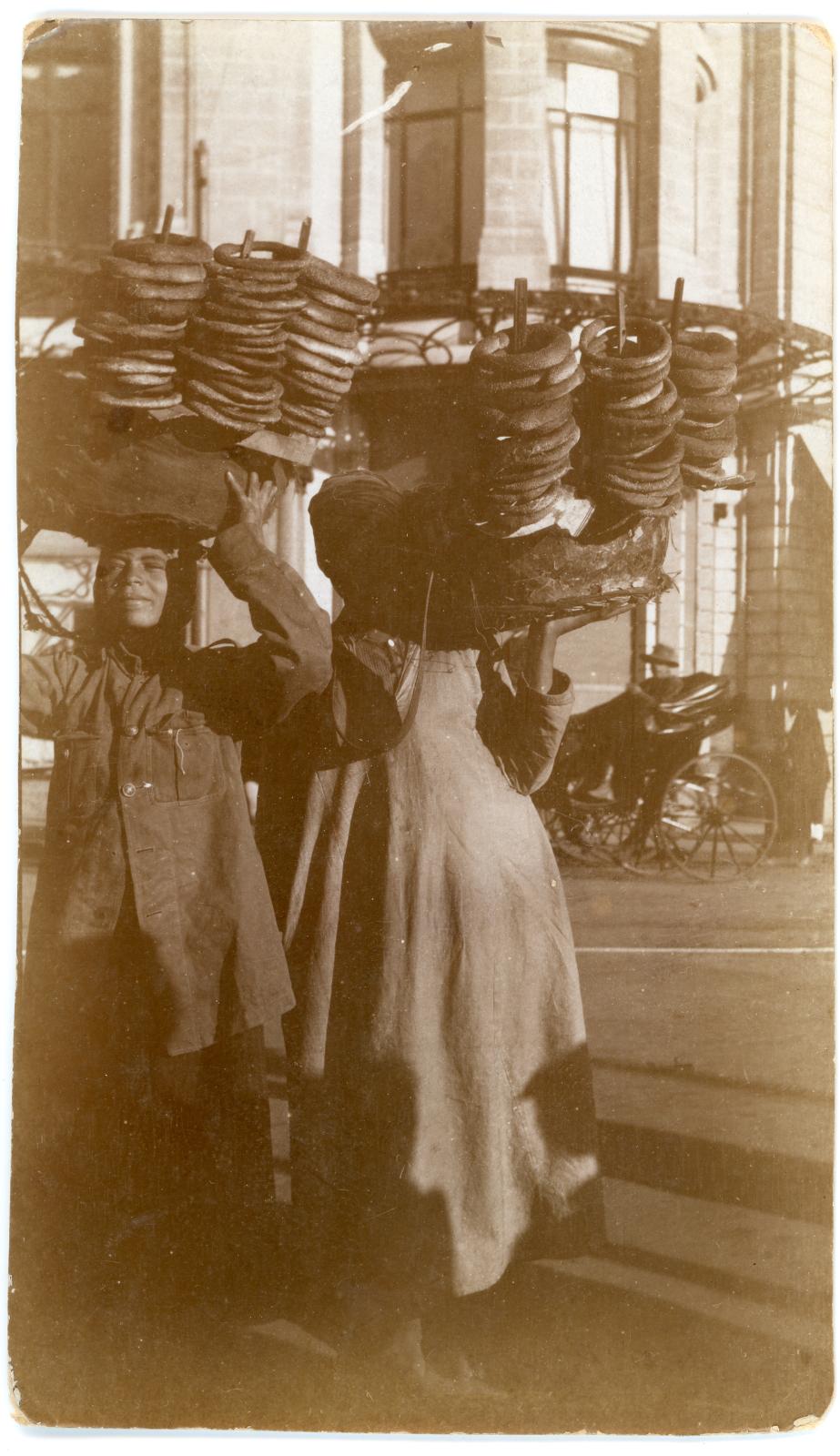 Photo showing 2 Egyptian women street vendors carrying bread rolls for sale.